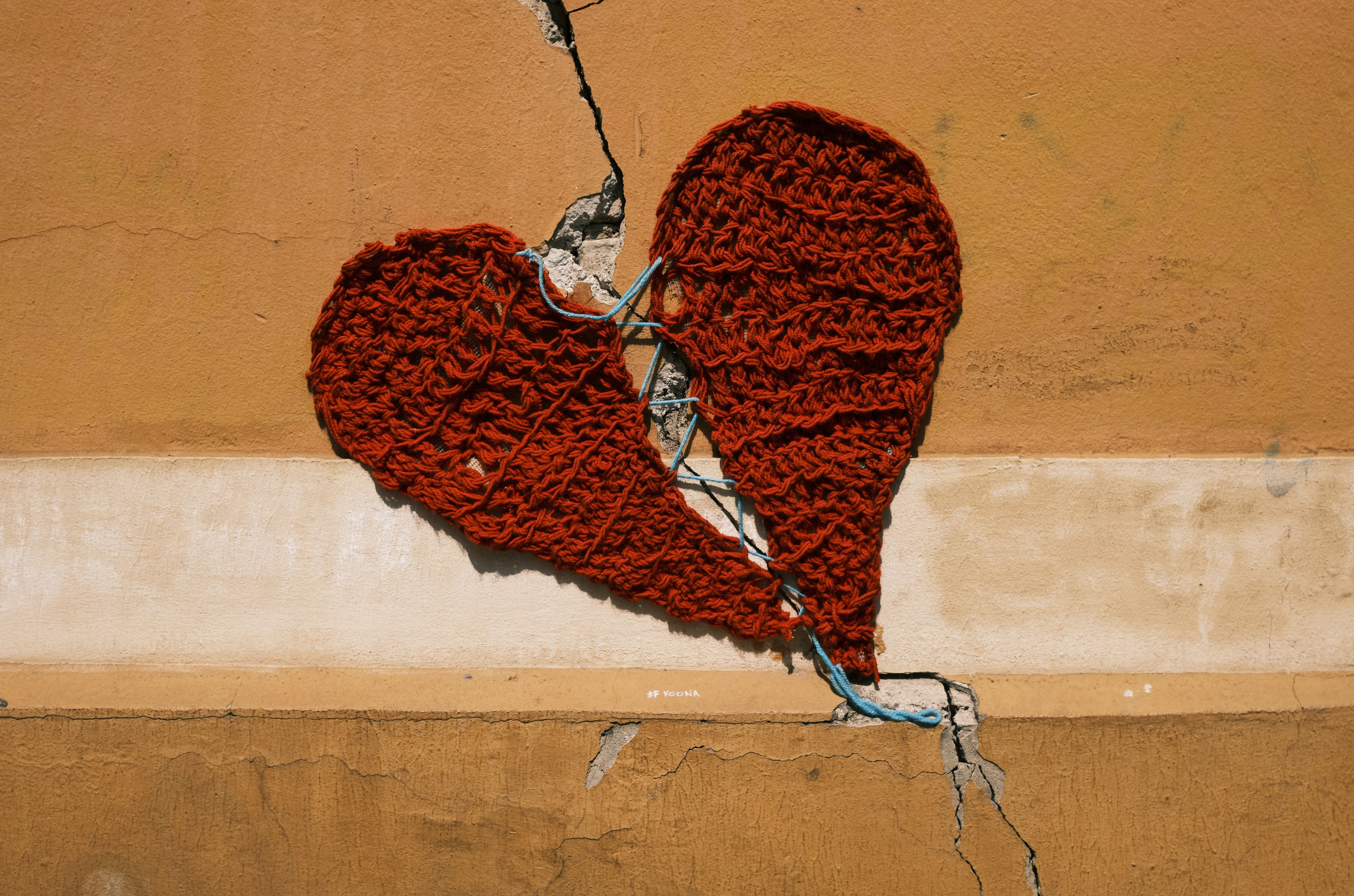 Knitted heart fixing a crack in a wall