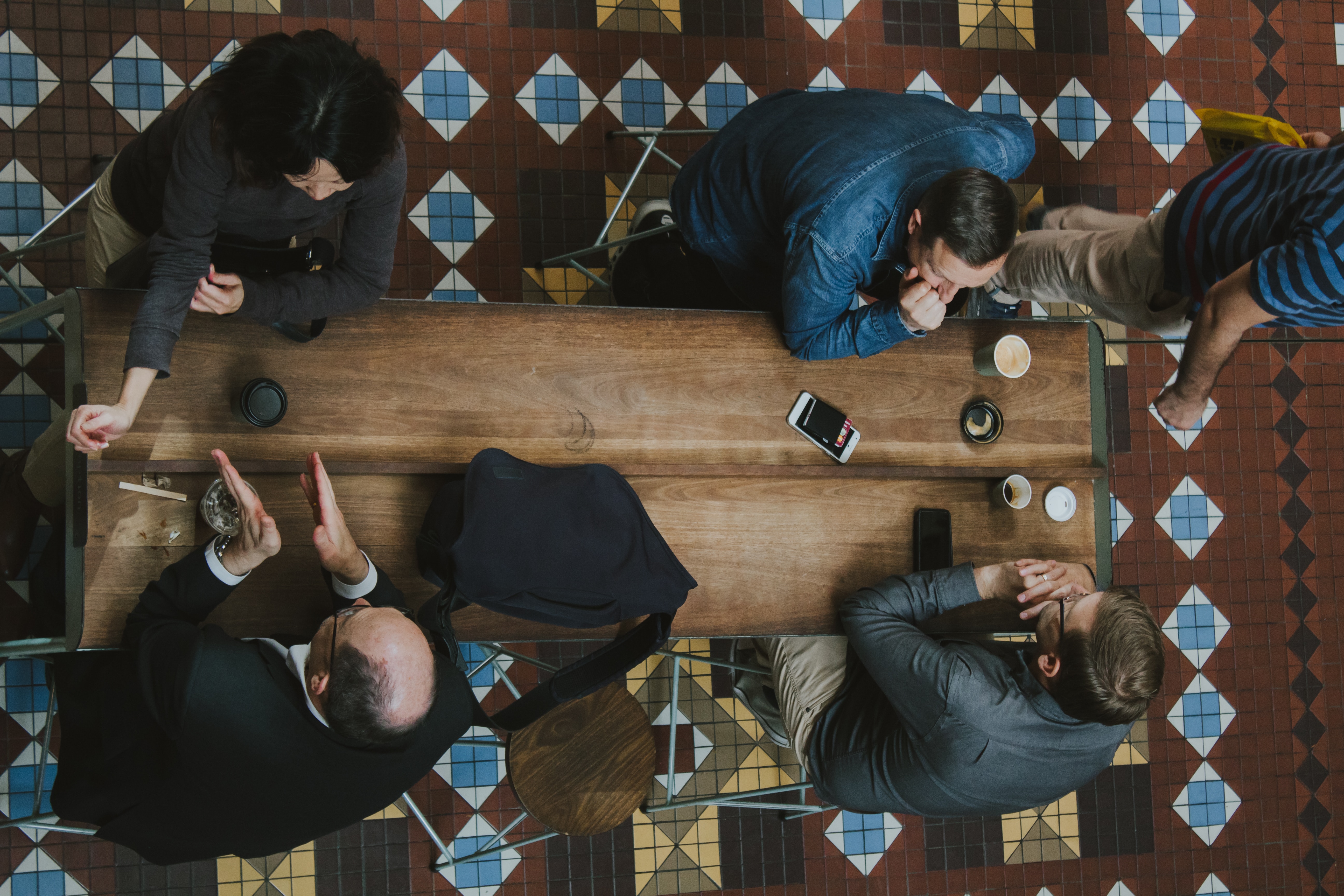 People sitting around a long wooden table and talking